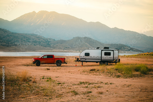 Canvastavla Pickup truck with travel trailer camping near lake in mountains at sunset, road