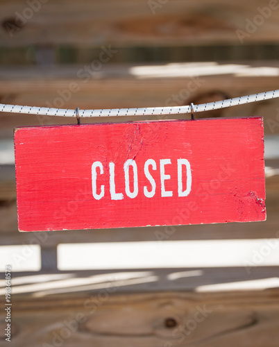 Red closed sign hanging on wooden background