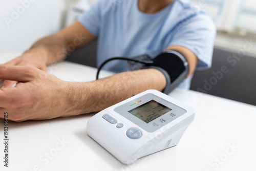 Digital blood pressure monitor in foreground during home medical check