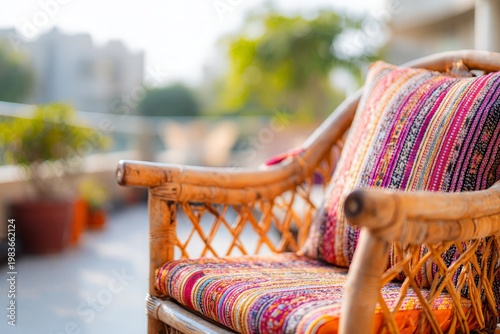 Woven bamboo chair with colorful patterned cushions on a blurred outdoor balcony background
