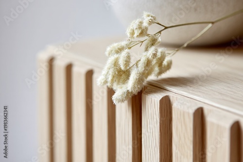 Dried grass rests on textured wooden surface in soft studio light