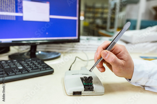 Bilde på lerret The developer holds the microprocessor with tweezers before placing it in the programmer