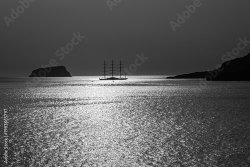 Beautiful view of a three masts sailing ship next to the volcano Palea Kameni in Santorini Greece in black and white