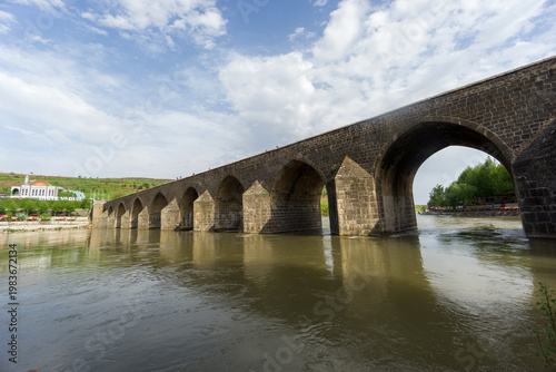 View of the historic Ten Arches Bridge (On Gozlu Bridge) spanning the Tigris River. Built during the Artuqid period, the stone bridge features multiple arches and reflects the architectural heritage o