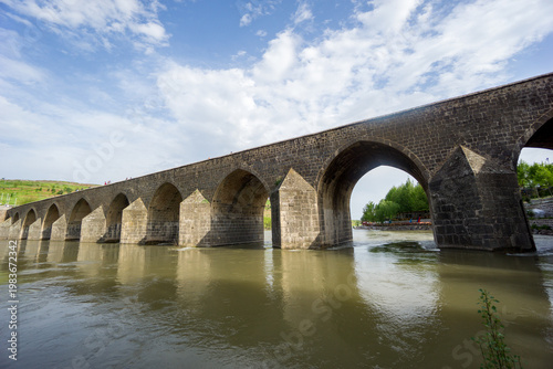 View of the historic Ten Arches Bridge (On Gozlu Bridge) spanning the Tigris River. Built during the Artuqid period, the stone bridge features multiple arches and reflects the architectural heritage o