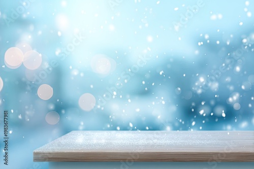 Empty wooden table with blurred blue winter background and falling snow.
