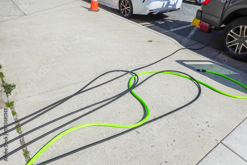Two garden hoses on concrete sidewalk