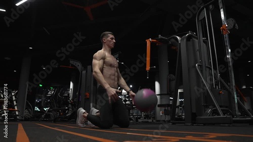 Fitness workout of sportsman with ball in gym. Sportsman do workout in fitness gym. Muscular man throw fitness ball on gym floor. Fit man ball workout in fitness gym. Ball workout