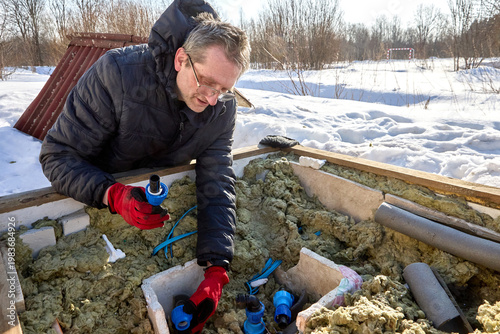 Connection of HDPE pipes with plastic compression fittings during installation of distribution piping in artesian well pit.