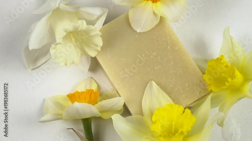 A bar of soap, fresh flowers daffodil are on a white background, cosmetics based on daffodils, top view