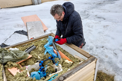 Plastic compression fitting for HDPE pipes in hands of homeowner installing distribution piping in artesian well pit.