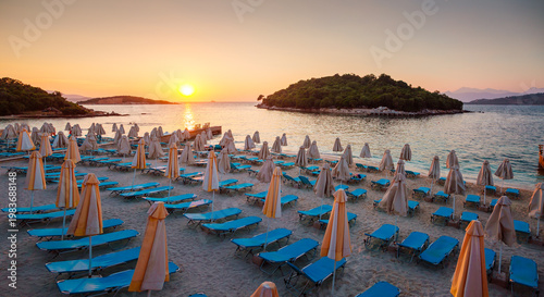 Serene beach at sunset and rows of lounge chairs with umbrellas overlooking tranquil seaside. Ksamil beach, Saranda, Albania, Europa.