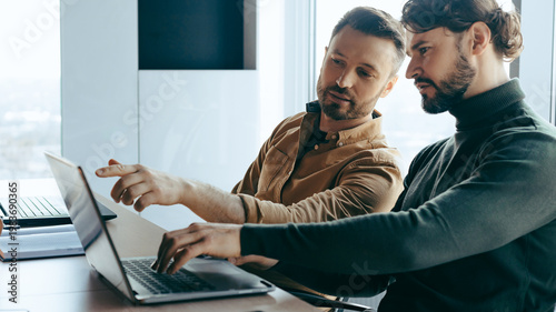 Foto Two men sit together at a table in an office