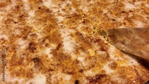 Freshly baked shortbread pie is cut into portions with a knife