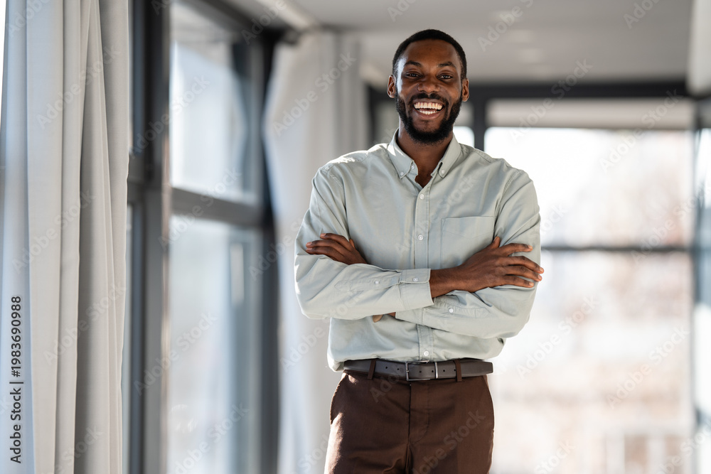 Obraz premium Confident african american businessman smiling with arms crossed