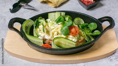 Foto Fresh green salad in cast iron skillet on wooden board, cucumber tomato and leaf