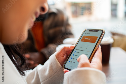 Person using mobile banking app at coffee shop table