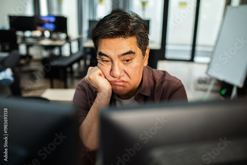 Bored male office worker staring at computer screen in modern workplace