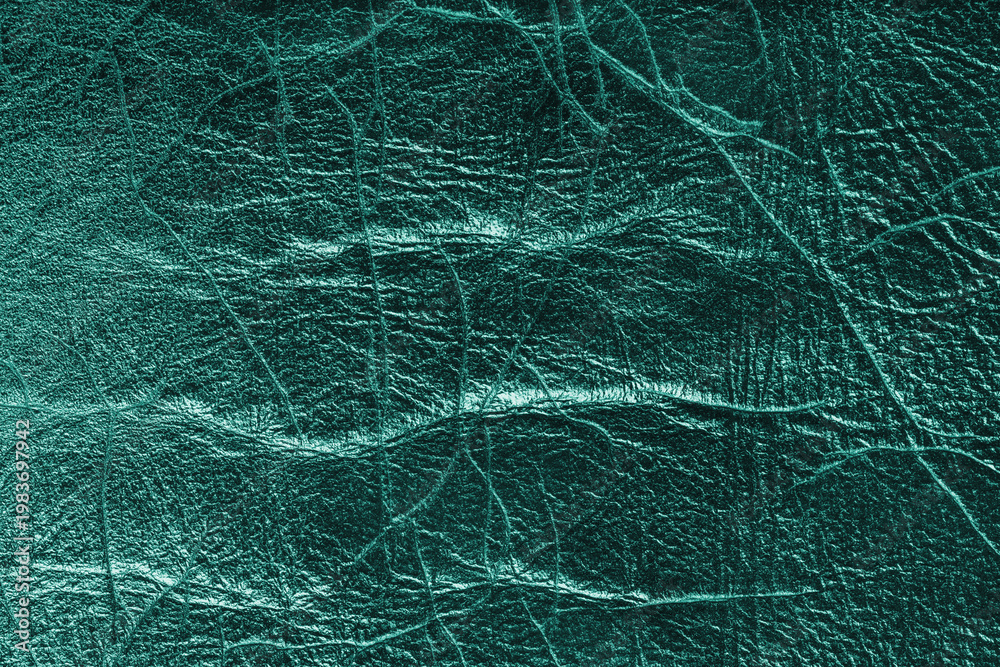 Fototapeta premium Detailed close up, macro of turquoise glossy metallic effect leather surface with visible wrinkles, creases and natural grain. Textured luxury material background, upholstery and design backdrop.