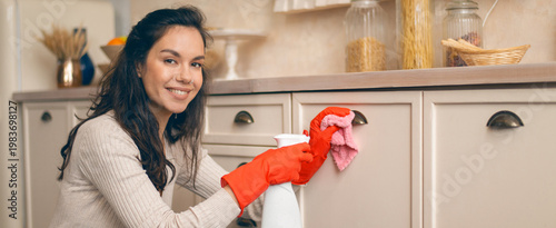 Fotografía A young woman is cleaning the kitchen counters while wearing red rubber gloves