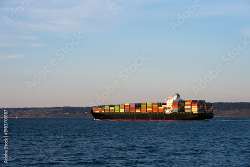 Fotografia Large container cargo ship transporting goods in Puget Sound at dusk, internatio