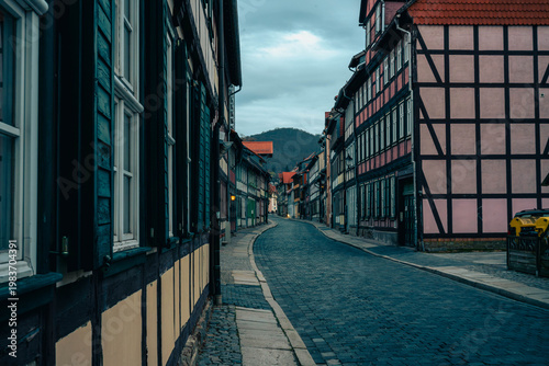 Blick durch eine historische Fachwerkgasse in Wernigerode mit Kopfsteinpflaster und Blick auf die Berge