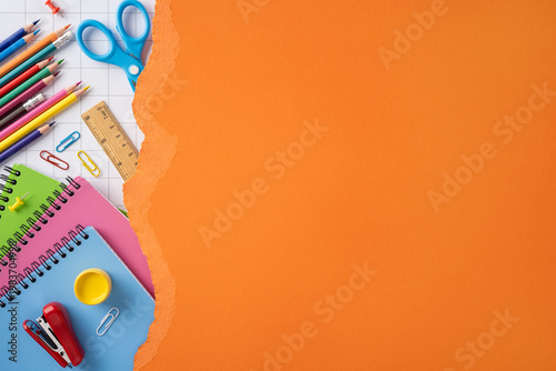 Bright back to school supplies on orange background with notebooks pencils and scissors for study and creativity
