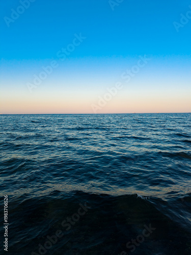 Fotografie Sunset over the ocean with blue sky and calm water at the horizon viewed from th