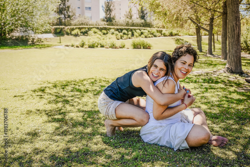 Mother and daughter embracing and smiling in park