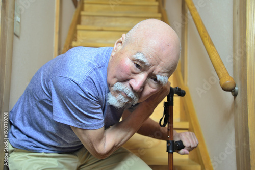 室内の階段で杖を使用してリハビリをしているヒゲの老人