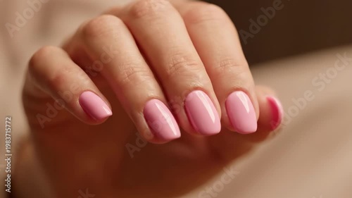Close-up of a womans hand with perfectly manicured pink nails, showcasing a fresh and elegant look.