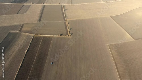 Aerial view shows brown plantless fields spreading across a great flat alluvial plain. Barren agricultural terrain and empty earth tones create stark open landscape from above.