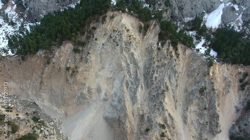 Aerial view of massive landslide tearing through forested mountain slope and exposed rock layers. Natural earth collapse shows landslip damage, unstable terrain, rugged geology and alpine.
