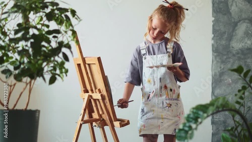 Child artist mixing colors on palette and painting picture. Creativity, learning and artistic skills development in cozy indoor studio with soft light and focused mood