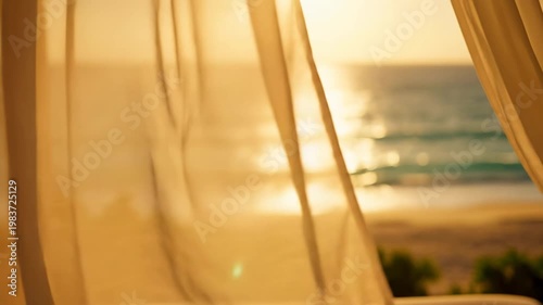 Golden hour view of a sparkling ocean and sandy beach through sheer, flowing curtains, creating a serene and dreamy atmosphere. Summer vacation aesthetic video.