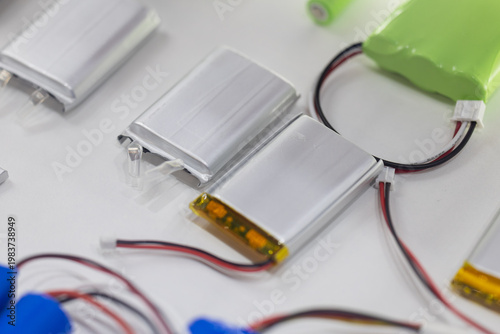 Silver lithium polymer battery packs with connecting wires on white. Compact energy solutions for small portable electronics. Lightweight rechargeable cells for modern gadgets