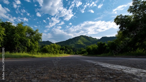 Rural Road Leading to Verdant Hills Under Cloudy Sky