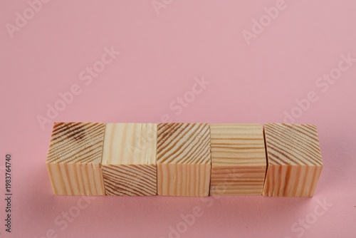 Blank wooden cubes on pink background, space for text