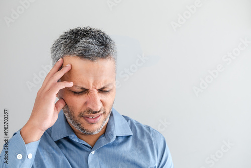 Stressed mature man suffering from headache holding his head