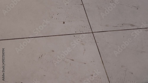 Footprints on tiled floor showing gradual progression of dirt marks across the surface, highlighting movement and activity in an indoor setting