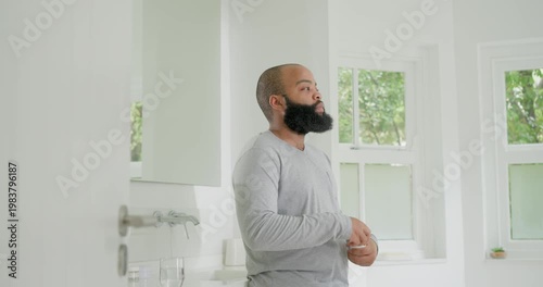 African American man checking wrists, opening pill bottle with red cap, taking medication at sink