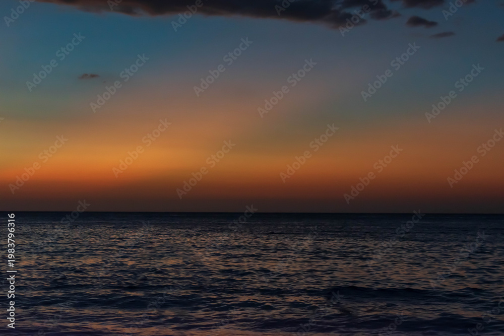 Fototapeta premium Beach scene at dusk, glowing horizon, and textured evening clouds