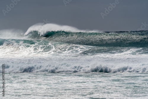 Bild auf Leinwand Powerful breaking wave with spray and whitewater under grey overcast sky
