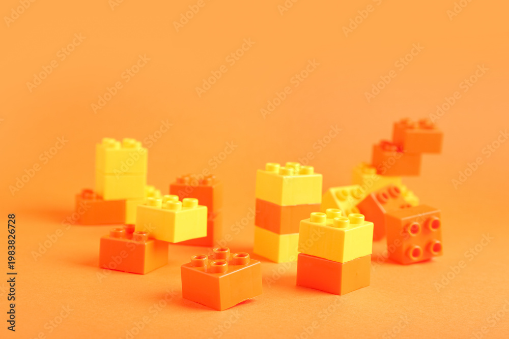 Naklejka premium Colorful plastic building blocks on orange background