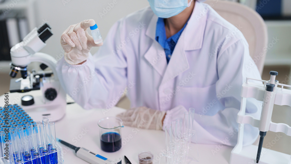 Fototapeta premium Adult Asian scientist researcher holds chemical sample vial laboratory testing medical discovery innovation development healthcare research facility scientific experiment