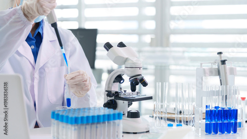 Fotografía Asian adult scientist conducts laboratory experiment pipetting blue liquid into