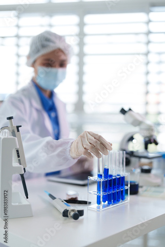 Adult Asian scientist experiment blue liquid test tubes laboratory medical research scientific discovery pharmaceutical biotechnology innovation
