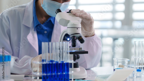 Asian adult scientist uses microscope conducting laboratory research experiment medical discovery healthcare innovation technology development science professional work