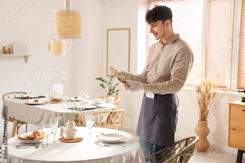 Young waiter setting table ...