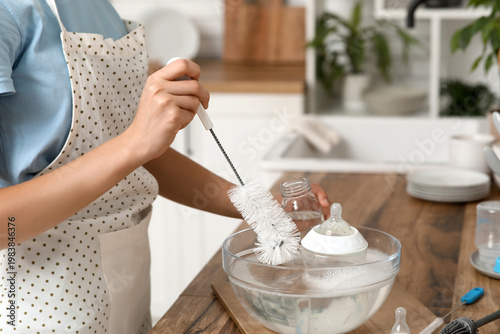 Woman cleaning baby bottle ...